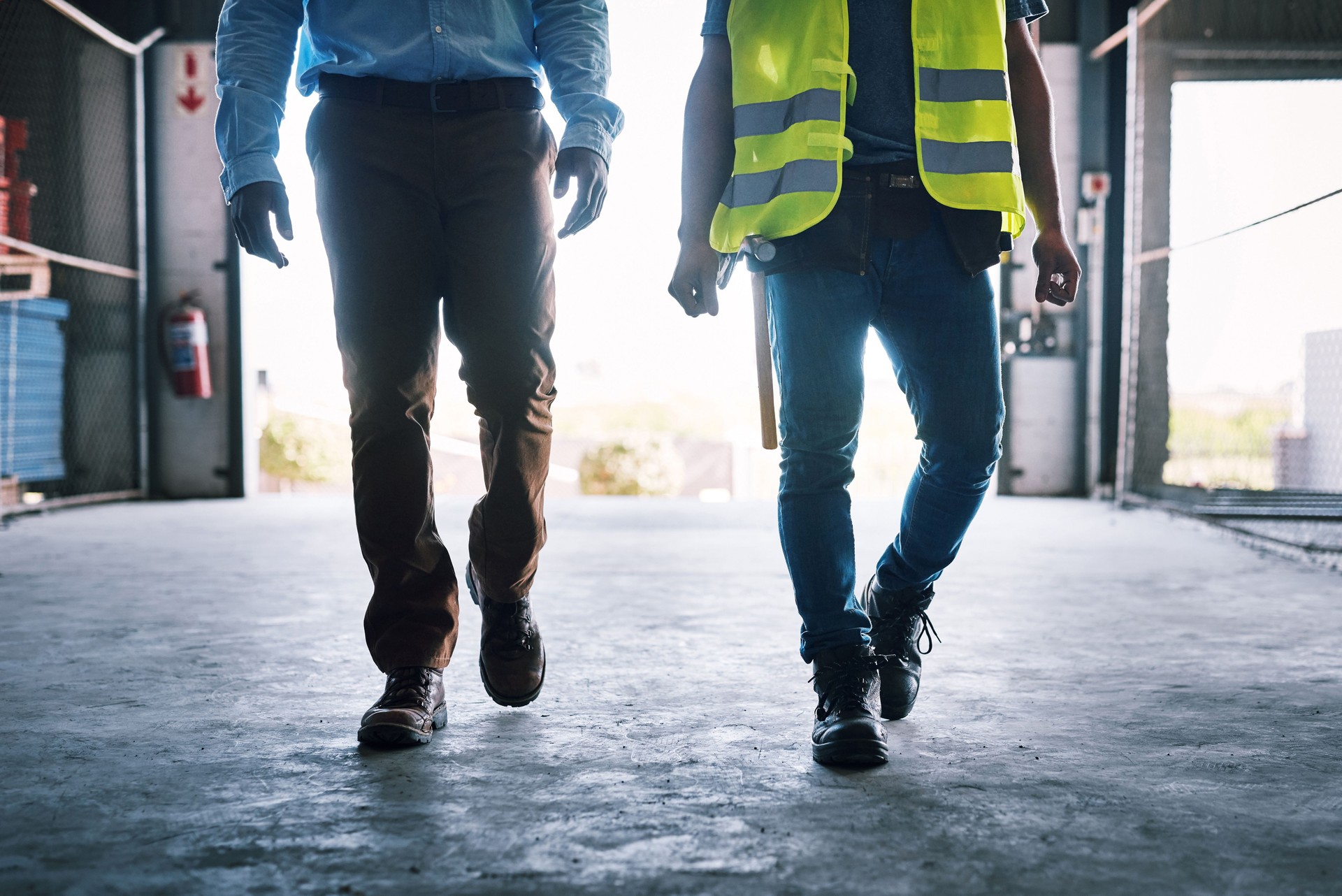 Foto de dos constructores irreconocibles caminando por un sitio de construcción